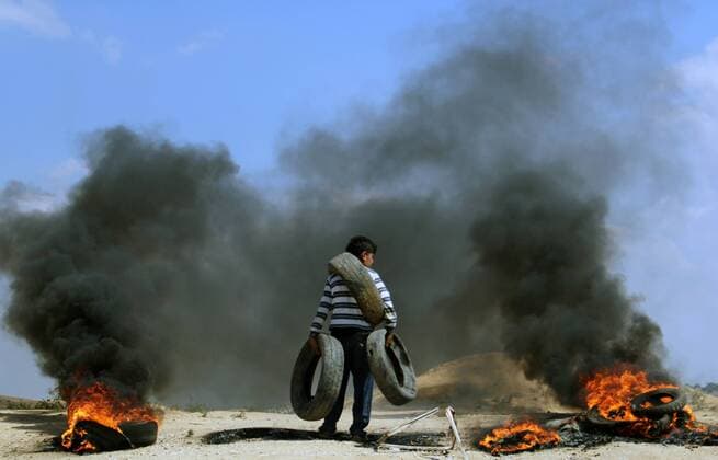 Sept. 20, 2010 - Jabalia, Gaza Strip, Palestinian Territory - A Palestinian youth carries tires during clashes with Israeli security forces near the border with Israel, east of Jabalia refugee camp in northern Gaza Strip, May 21, 2014 .Rallies in support of the hunger-striking prisoners took place in the West Bank and Gaza Strip on Friday, after the Coalition of Youth of the Intifada, Hamas, and Islamic Jihad called for a Friday of Anger - ZUMAap3_ 20100920_zaf_ap3_001 Copyright: xKhaledxAl-Sabbahx
