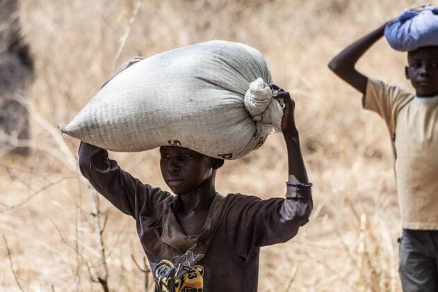 Mass exodus in Central Equatoria - 09 02 2017 - Uganda - A young boy carrying a bag on his head crosses the Ugandan border at Lefori area, Moyo district, heading to the nearby Lefori collection point. Most refugees (86%) fleeing South Sudan are women and children, including survivors of violent attacks and sexual assault, and children that have been separated from their parents, travelled alone or have become primary caregivers to younger siblings. -  NataliaxJidovanux xLexPictorium LePictorium_0153915