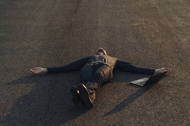 IMAGO Creative: Gesundheit, Burnout Businessman lying on a road next to laptop model released Symbolfoto  KNSF01124