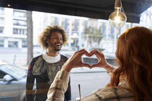 Woman shaping heart with her hands for man behind windowpane model released Symbolfoto property released  FMKF03497