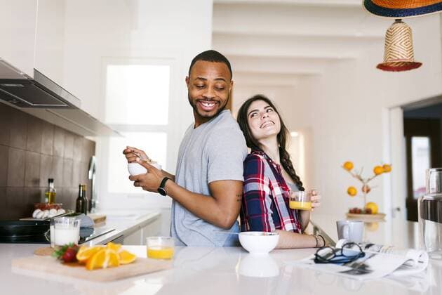 Young couple having breakfast in the kitchen, standing back to back model released Symbolfoto property released  VABF01204