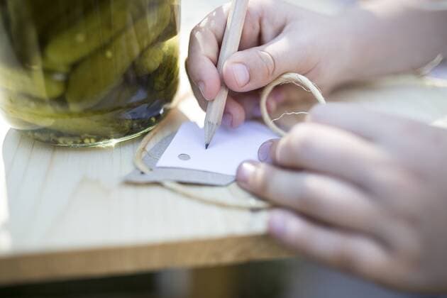 Girl writing on label next to jar with preserved gherkins model released Symbolfoto  WESTF22820