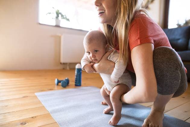 Smiling mother with baby and dumbbells at home model released Symbolfoto property released  HAPF01367