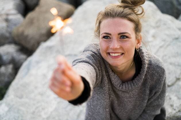 Portrait of smiling young woman holding sparkler outdoors model released Symbolfoto  KKAF00575