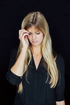IMAGO Creative: Gesundheit, Burnout Portrait of suffering blond woman in front of black background model released Symbolfoto  CHAF01803
