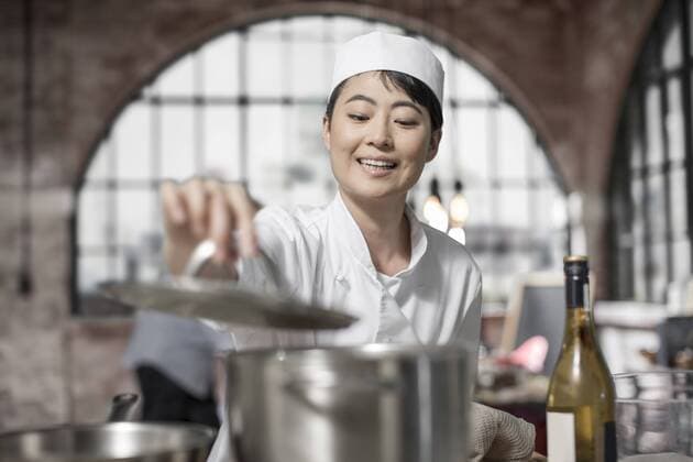 Smiling female chef cooking in kitchen model released Symbolfoto property released  ZEF13488