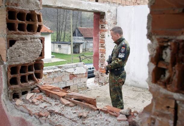 Deutscher SFOR - Soldat haelt Wache in einem zerstoerten Haus in Drozgometva , einem Gebiet serbischer Heimkehrer in Bosnien-Herzegowina , Bundeswehr , Auslandseinsatz , Wiederaufbau , CIMIC - Projekt , Ausland , 17.04.2003, Drozgometva Bosnien-Herzegowina Copyright: xT.xKxoxexhxlxexr.x