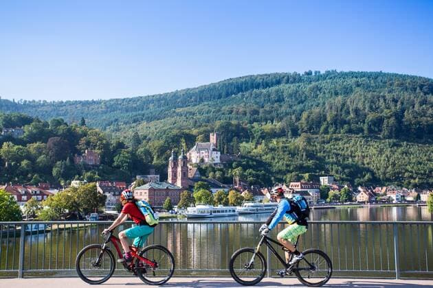 Mountainbiker auf einer Brücke über den Main mit blick auf die Altstadt von Miltenberg Miltenberg Deutschland Odenwald