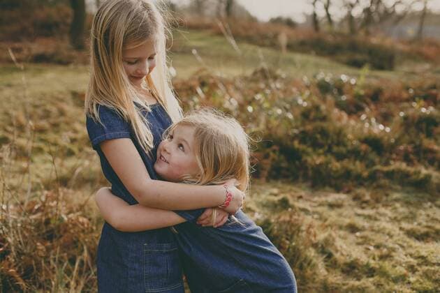 Two cute blond sisters cuddling outdoors model released Symbolfoto  NMSF00104