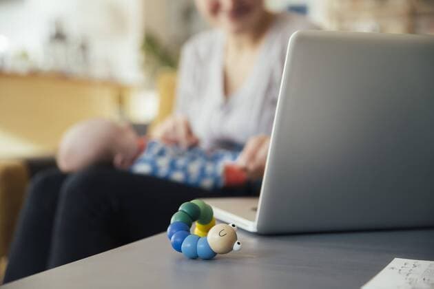 Baby toy next to laptop of mother holding her newborn baby at home model released Symbolfoto property released  MFF03580