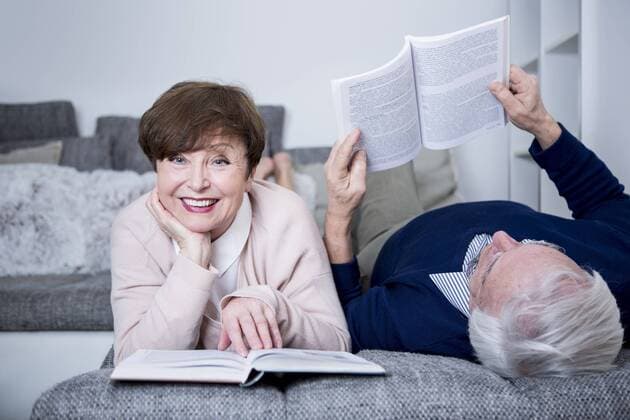 Senior couple lying on couch, reading books model released Symbolfoto property released  WESTF23275