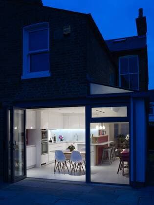 Designklassiker von Ray und Charles Eames Patio, rear facade and view of kitchen through open glass doors at night, residential house, UK United Kingdom  Copyright: xAlistairxNichollsx 14735-160-1