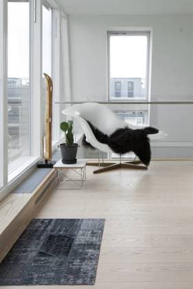 No nonsense, Modern apartment in Copenhagen. A monochrome decorative scheme, with subtle colour accents. A white Eames style chair with a black throw. Denmark  Copyright: xJensxBarslundx 15376-280-1
