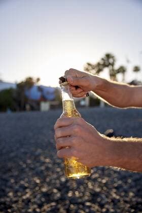 Man s hands opening beer bottle on the beach model released Symbolfoto  PACF00029