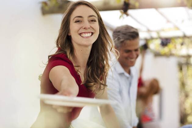 Smiling woman handing over plate on agarden party model released Symbolfoto property released  ZEF13961