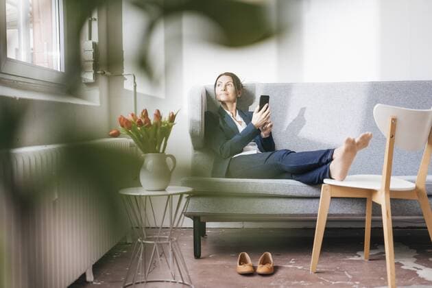 Businesswoman sitting on couch in a loft looking out of the window model released Symbolfoto property released  JOSF01171