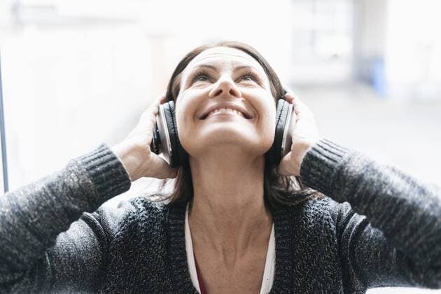 Portrait of smiling woman listening music with headphones looking up model released Symbolfoto property released  JOSF01226