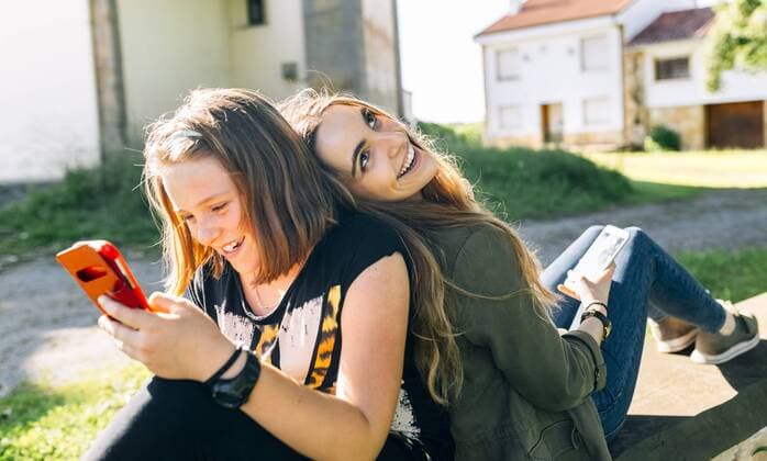 Two happy girls using their smartphones outdoors model released Symbolfoto  MGOF03443