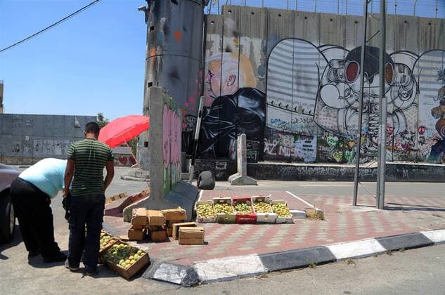 August 6, 2017 - Bethlehem, West Bank, Palestinian Territory - A Palestinian vendor sells vegetables in front of a graffiti depicting US President Donald Trump on the controversial Israeli separation barrier in the West Bank town of Bethlehem on August 8, 2017 Bethlehem Palestinian Territory - ZUMAap3_ 20170806_zaf_ap3_039 Copyright: xShadixHatemx