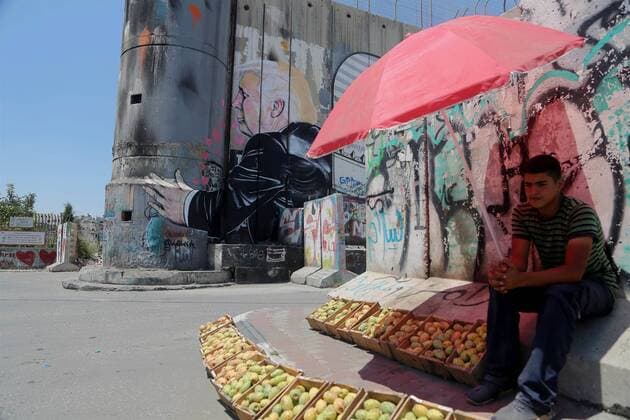 August 6, 2017 - Bethlehem, West Bank, Palestinian Territory - A Palestinian vendor sells vegetables in front of a graffiti depicting US President Donald Trump on the controversial Israeli separation barrier in the West Bank town of Bethlehem on August 8, 2017 Bethlehem Palestinian Territory - ZUMAap3_ 20170806_zaf_ap3_042 Copyright: xShadixHatemx