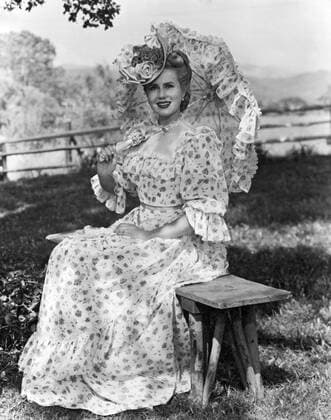 United States: c. 1940 An attractive young woman in Victorian dress seated on a bench and holding a parasol. xUnderwoodxArchives 3-Fash-W-Vict_8 990_05_3-Fash-W-Vict_8HR