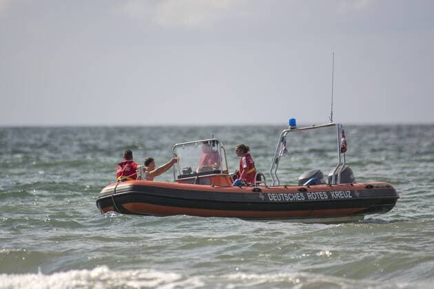Ein Schlauchboot mit Rettungsschwimmern vom DRK kreuzen am Badestrand vom Ostseebad Rostock-Warnemuende, Etwa 1.800 Rettungsschwimmer der Wasserwacht des Deutschen Roten Kreuzes haben von Mai bis September gut 14 Ostseestraenden und knapp 60 Badestellen an Binnengewaessern im Urlaberland MV überwacht. Um möglichst viele Unfälle auf und im Wasser zu verhindern, leisten die Ehrenamtlichen eine sehr wichtige präventive Arbeit an den Stränden. So werden werden ducrh das DRK Nichtschwimmer, meistens Kinder, aber auch Jugendliche und Erwachsene, zu Schwimmern und Rettungsschwimmern ausgebildet. Rostock Warnemünde Copyright: FrankxHormannx xnordlicht