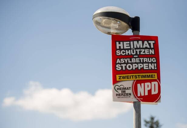 Ein Wahlplakat mit der Aufschrift Heimat schützen - Asylbetrug stoppen der NPD, aufgenommen am Montag (28.08.2017) an einem Lampenmast in Struppen in der Sächsischen Schweiz. *** a Election billboard with the Inscription Home protect Asylum fraud stop the NPD Date at Monday 28 08 2017 to a Lamp pole in Strupp in the Saxon Switzerland RM001