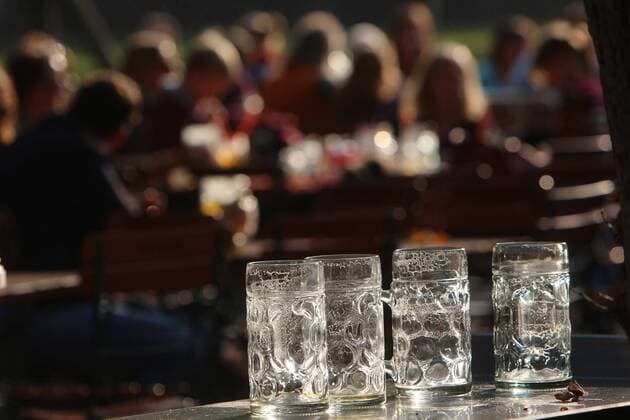 spätsommerliche Temperaturen und schönster Sonnenschein lockten viele Sonnenhungrige in den Biergarten Königlicher Hirschgarten in München, Bayern, Deutschland. Geleerte Mass Bier im Gegenlicht der Nachmittagssonne