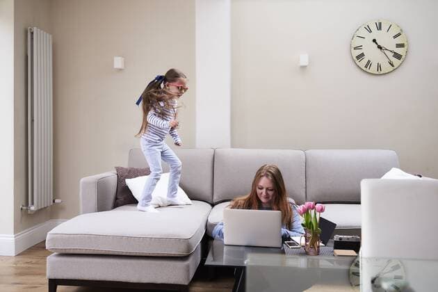 Little girl wearing sunglasses jumping on sofa while her mother working on laptop at coffee table model released Symbolfoto property released  IGGF00018