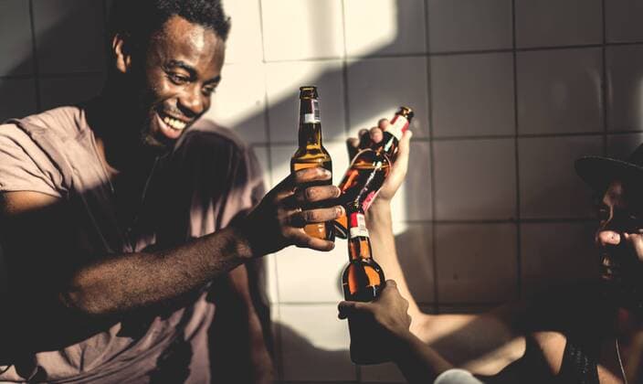 Two smiling men sitting indoors, holding beer bottles, toasting. Two smiling men sitting indoors, holding beer bottles, toasting.  33205