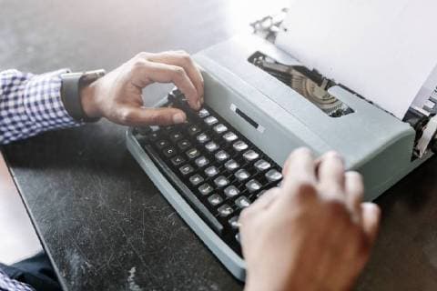 Close-up of man at desk using typewriter model released Symbolfoto  GIOF03137