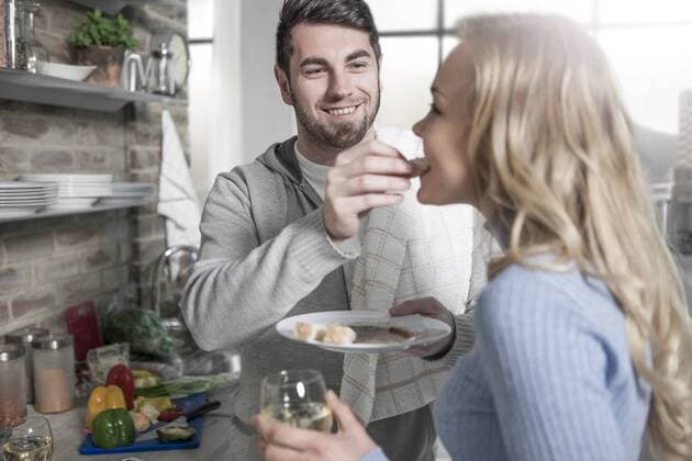 Couple tasting food together in kitchen model released Symbolfoto property released  ZEF14474