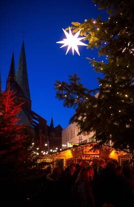 Lübecker Weihnachtsmarkt Beleuchtete Weihnachtssterne hängen am 02.12.2016 auf dem Weihnachtsmarkt Sternenwald auf den Schrangen in Lübeck. Im Hintergrund ist der Dom zu Lübeck zu sehen. Luebeck Schleswig-Holstein Germany