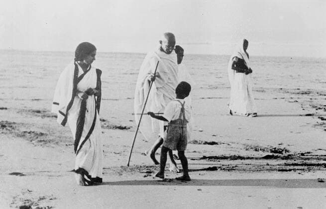 IMAGO ICONS: Mahatma Gandhi Gandhi recuperates at the seaside after illness. Mahatma Gandhi, the Indian nationalist leader, is recuperating at the seaside from his recent illness. He is staying at juhu, Bombay, and takes a regular morning walk on the beach. Photo shows, Mahatma Gandhi, talking to a small companion during his morning walk on the beach at Juhu, Bombay. 11 January 1938, India Copyright: Topfoto  UnitedArchivesEU055013