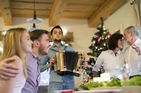 Young man playing accordion for family at Christmas model released Symbolfoto property released  HAPF02209