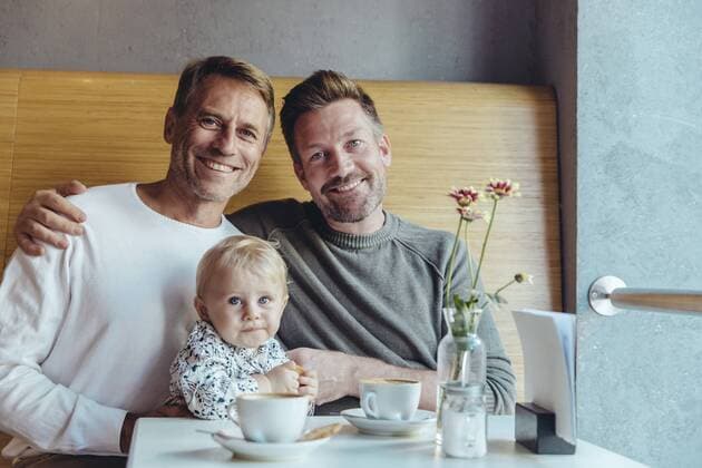 Portrait of happy gay couple with their baby in cafe model released Symbolfoto property released  MFF03884