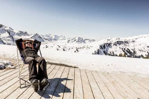 Austria, Damuels, woman relaxing in deckchair on sun deck in winter landscape model released Symbolfoto  PNPF00056