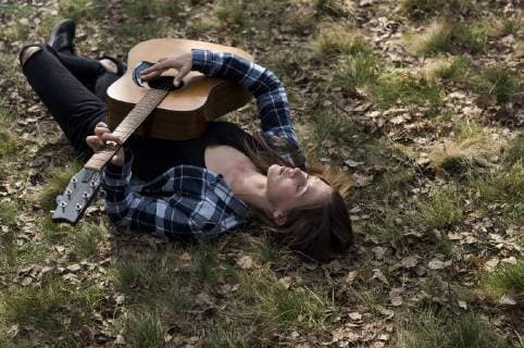 Woman lying on meadow playing guitar model released Symbolfoto  ZOCF00515