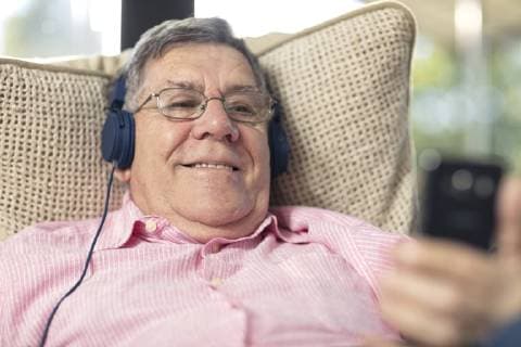 Smiling senior man wearing headphones listening to music at home model released Symbolfoto property released  ZEF14727