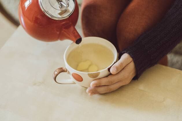 Woman pouring water into tea cup with chopped fresh ginger, close-up model released Symbolfoto property released  JSCF00023