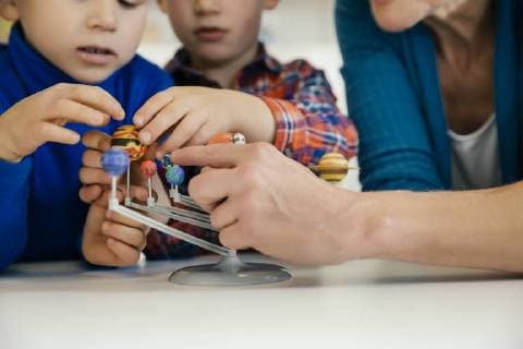 IMAGO Creative: Bildung, Wissenschaftserziehung Pre-school teacher and boys exploring solar system model in kindergarten model released Symbolfoto property released  MFF04125