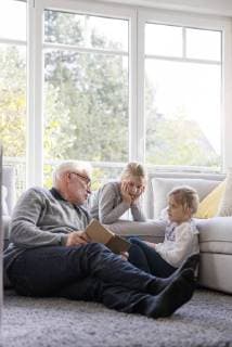 Two girls and grandfather reading book in living room model released Symbolfoto property released  MOEF00529