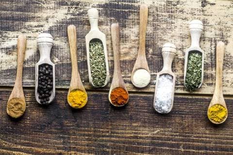 Spicies, curry, chilli, cinnamon, curcuma, garlic, parsley, oregano, salt and pepper on wooden spoons  SARF03463