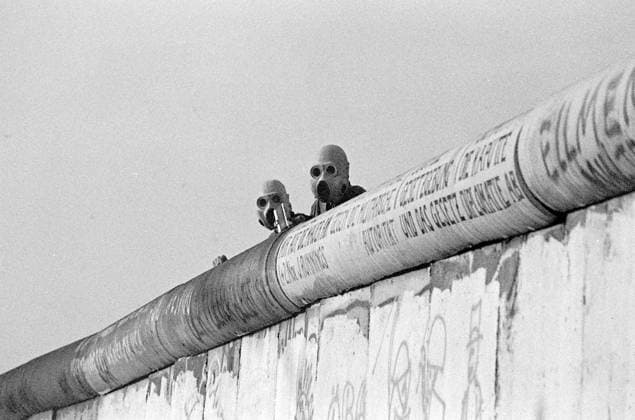 Berliner Mauer- Juni 1988 DDR-Grenzsoldaten beobachten auf der Mauer mit aufgesetzten Gasmasken gewalttaetige Auseinandersetzungen zwischen der Westberliner Polizei und den autonomen Besetzern des Lenné-Dreiecks am Potsdamer Platz.