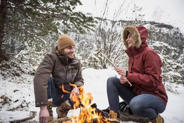 Happy couple on a trip in winter having a break at camp fire model released Symbolfoto  SUF00447