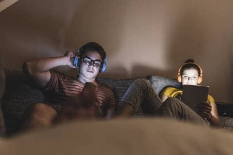 IMAGO Creative, Weihnachten, Tradition: Weihnachtsfilme sehen Couple with headphones relaxing on couch at home model released Symbolfoto property released  UUF12517