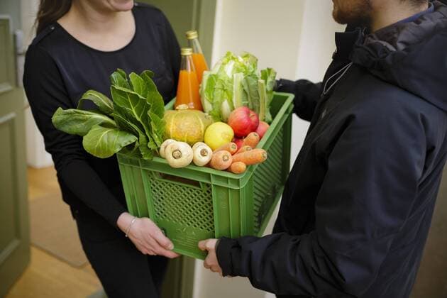 Gestellte Aufnahme: Eine Biokiste mit Obst und Gemuese wird von einem Lieferanten an der Haustuer uebergeben. Berlin, 01.03.2018. Berlin Deutschland