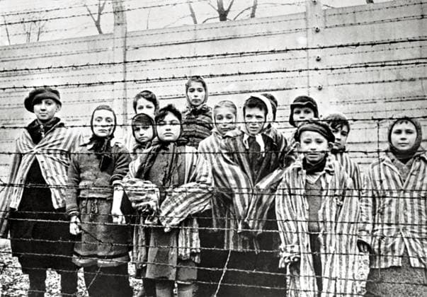 Überlebende jüdische Kinder in Auschwitz Mit Krankenschwester hinter Stacheldrahtzaun. Das Foto wurde von einem sowjetischen Fotografen während der Herstellung eines Films über Befreiung des Lagers gemacht. Die Kinder wurden von den Russen mit Kleidung von erwachsenen Gefangenen verkleidet. Auschwitz, Polen. Datum: Februar 1945