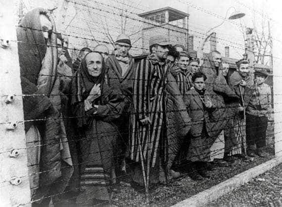Überlebende von Auschwitz hinter Stacheldrahtzaun. Foto von einem sowjetischen Fotografen während der Herstellung eines Films über die Befreiung des Lagers gemacht. Auschwitz, Polen. Datum: Februar 1945