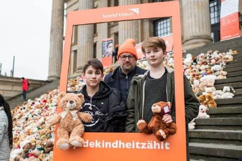 Kinder und Jugendliche haben am Donnerstag (15.03.18) auf der Treppe zum Konzerthaus am Berliner Gendarmenmarkt ein Mahnmal aus 740 gespendeten Teddybaeren errichtet. Foto: Christoph Waffenschmidt, Vorstandsvorsitzender von World Vision Deutschland mit Kindern. Mit einer Teddybaeren-Aktion hat die Hilfsorganisation World Vision Deutschland zum siebten Jahrestag des Kriegsbeginns auf das Leid der Kinder in Syrien aufmerksam gemacht. Bei dem Mahnmal steht jeder Teddy fuer 1.000 Kinder im Schulalter auf der Flucht. Die Baeren sollen anschliessend an gefluechtete Kinder in Berlin und in Jordanien verteilt werden. (Siehe epd-Meldung vom 15.03.2018) Syrien-Mahnmal aus 740 Teddybaeren